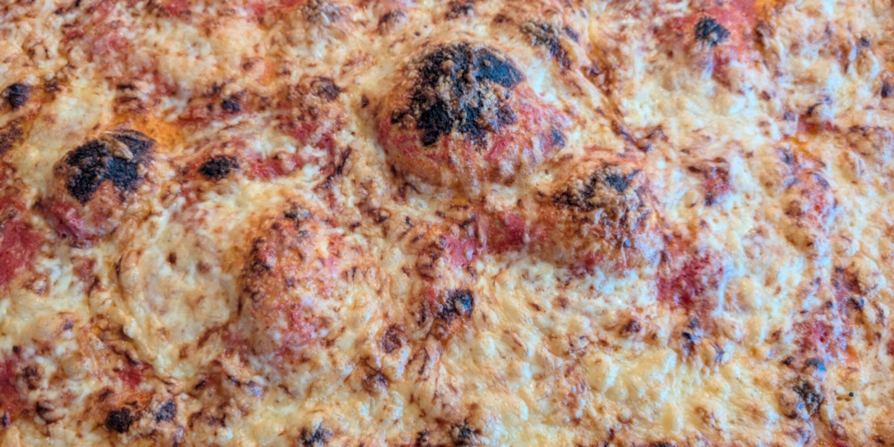 Fertige Pizza mit zerlaufenem, geröstetem Käse