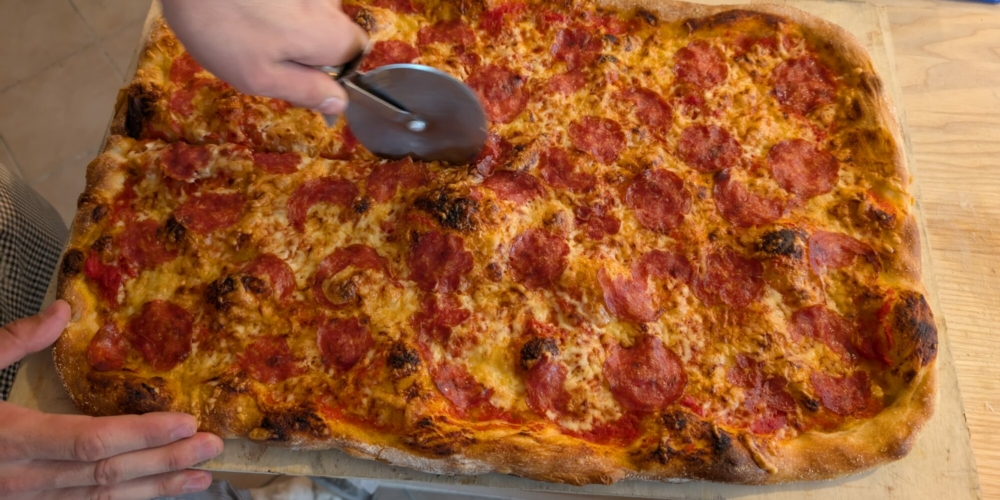 Eine Salami-Pizza wird geschnitten