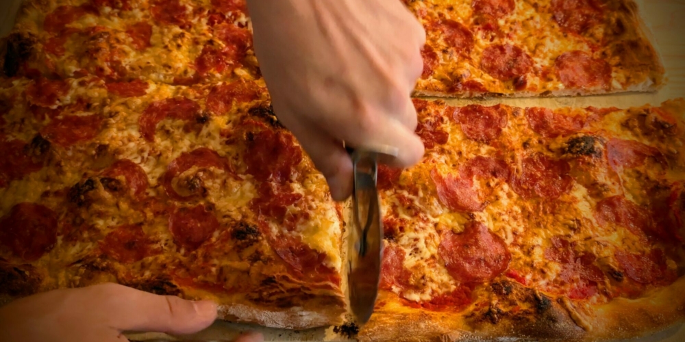 Eine Salami-Pizza wird aufgeteilt